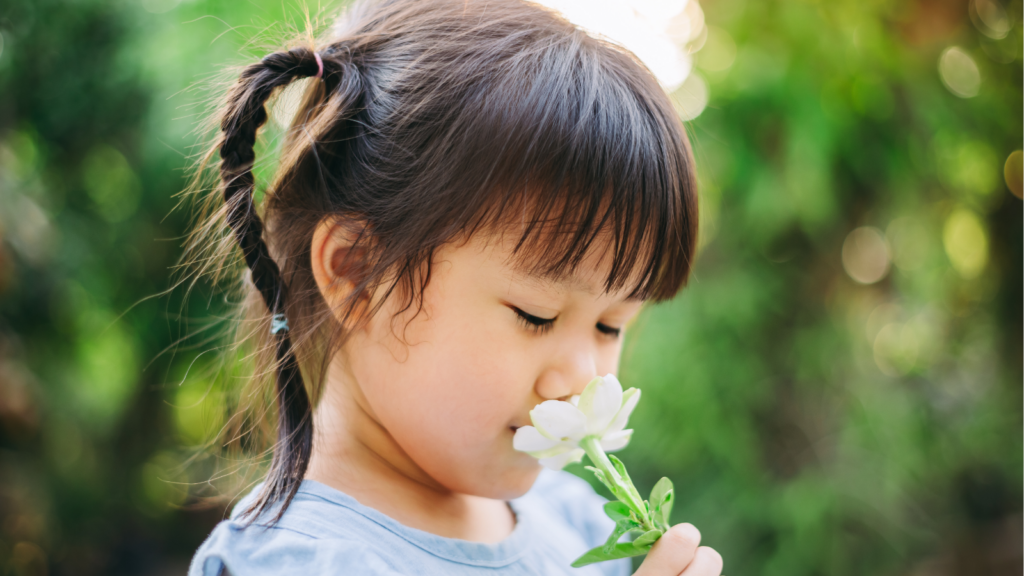 young girl smelling a flower