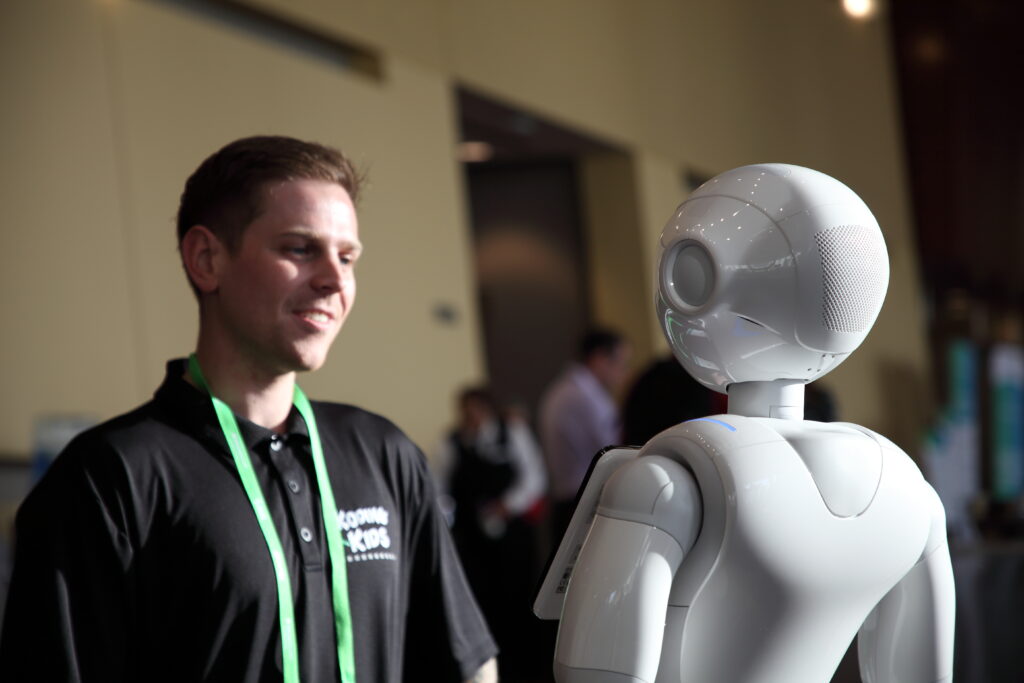 man standing with pepper the robot